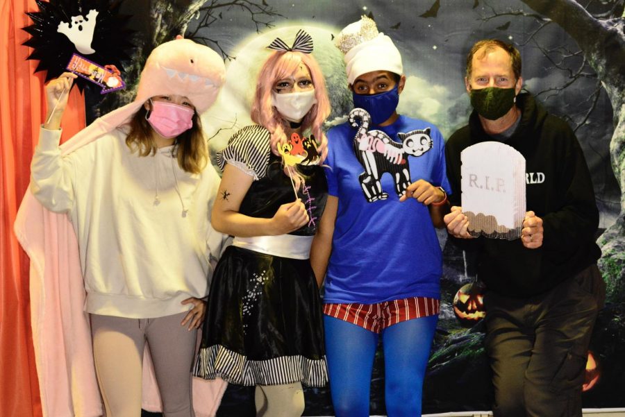 Students and teacher pose in front of a spooky backdrop at the Halloween event (From left to right: Maddie Tsang, Sophia Trabanino, Reece Sharp, Julian Cortella).