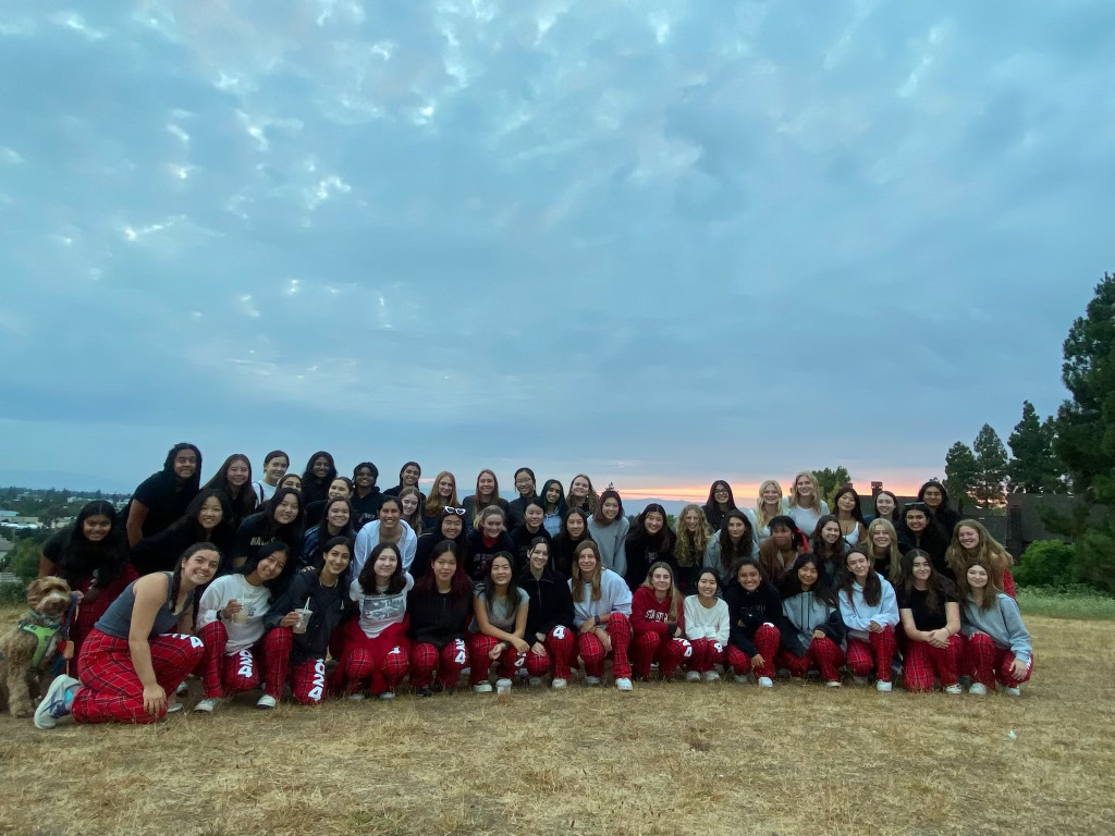 The current seniors, class of 2024, pose for a photo in front of the sunset during the annual senior sunrise.